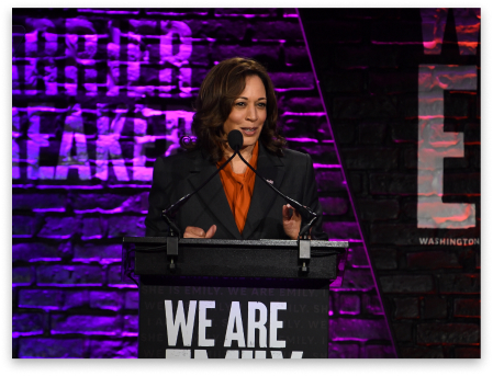 Kamala Harris speaking at a podium at the 2022 We Are Emily Gala.